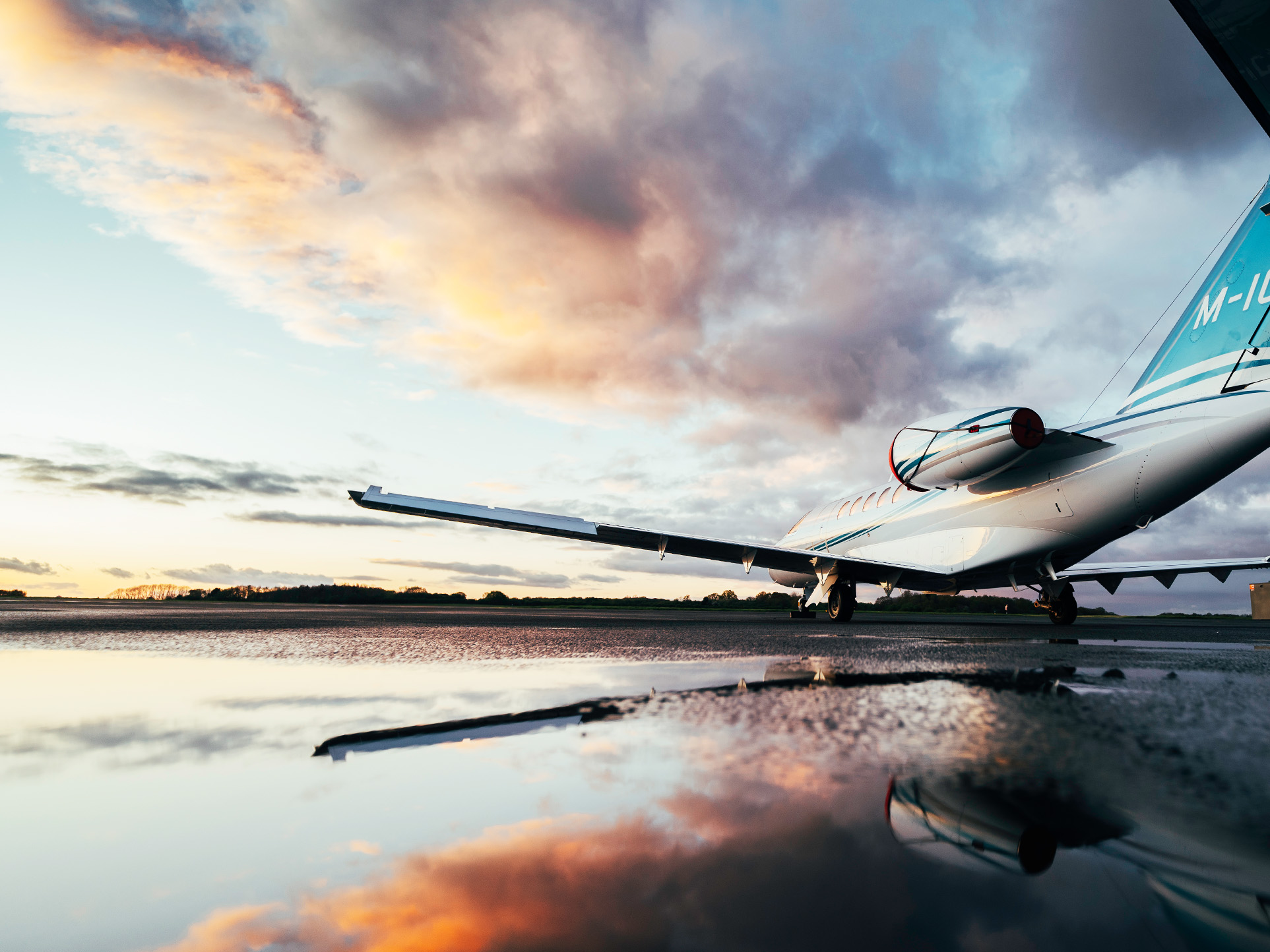 Aircraft sat on the apron with cloud reflections on the wet ground.