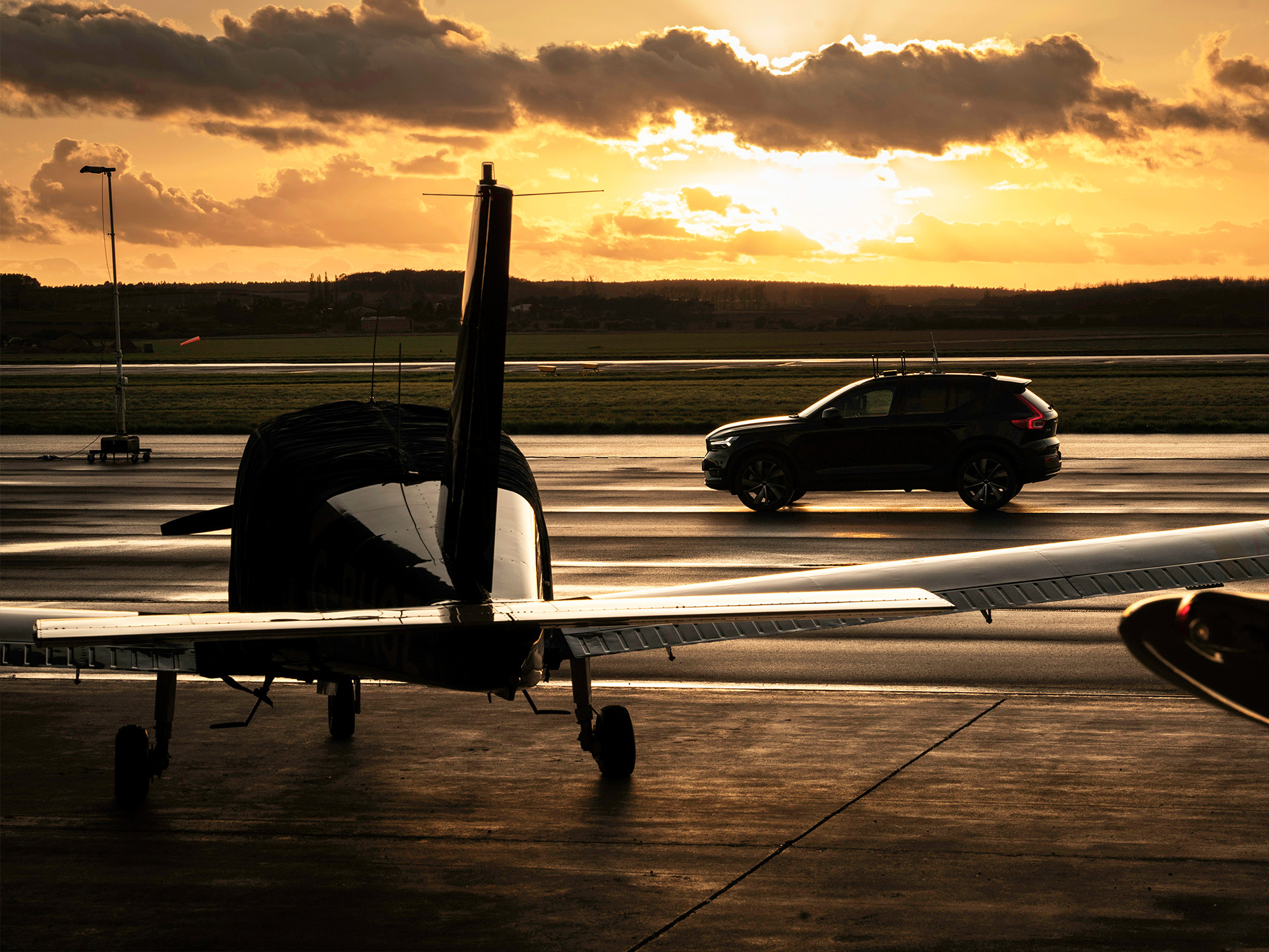 Aircraft at sunset with a car driving past.